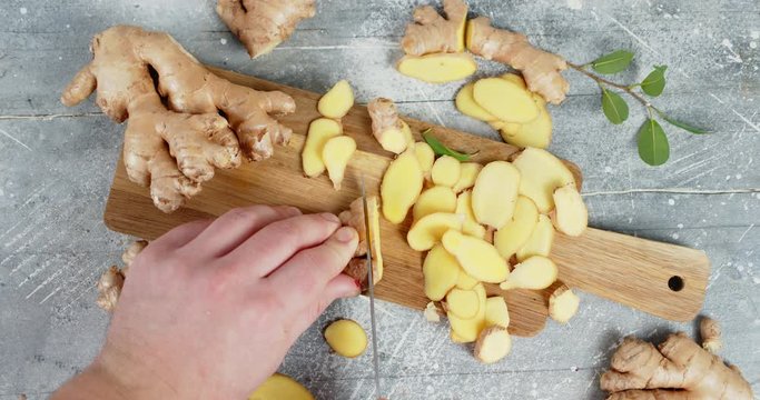 Male hand with a knife slice the ginger on a cutting Board.