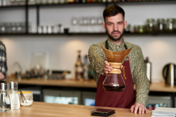 Professional barista preparing coffee using chemex pour over coffee maker and drip kettle....