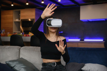 VR. Excited Millennial Girl Using Virtual Reality Headset Playing Videogame Indoor. Selective Focus