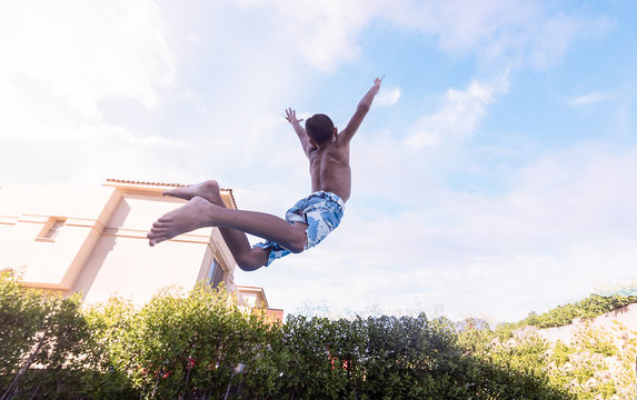 Low Angle View Of Shirtless Boy Jumping Against Sky