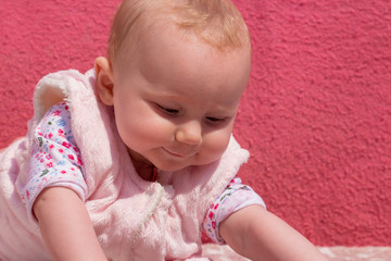 Little adorable blonde baby girl stands on her hands and this cute baby smiling