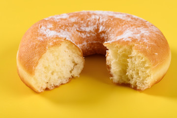 donut with some bites on a yellow background