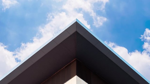 Abstract symmetry geometry triangular high building with timelapse clouds motion on blue sky in sunny day, Urban modern architecture creative design concept