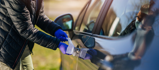 Woman with protective gloves disinfecting the car with antibacterial wet wipes.