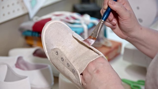 Person crafting as they hand paint shoes for hobby at home.