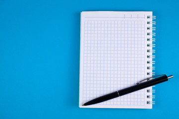 Pen and notepad on a blue background. Copy space. Top view.