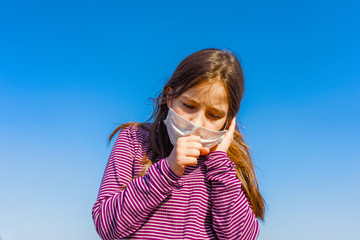 Portrait of little girl wearing a protective medical mask and coughs. epidemic of the flu, Coronavirus or COVID-19