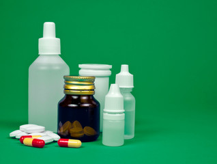 Medicine bottles with pills on a green background.