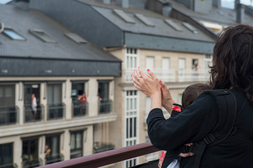 a mother and her baby applauding from the balcony in solidarity with the health personnel who are...