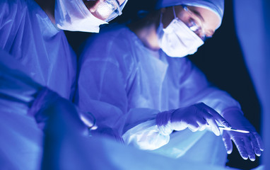 Doctors team in surgery in a dark background.