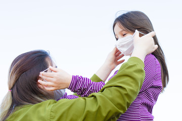 mother help her daughter wearing medical mask for protection covid 19
