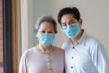 An elderly Asian couple wearing masks