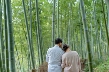 An elderly Asian couple walking in a bamboo forest