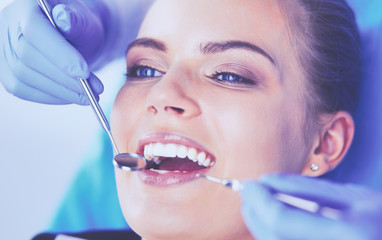 Young Female patient with open mouth examining dental inspection at dentist office.