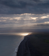 Sun shining through clouds on the coast, landscape in Vik, Iceland
