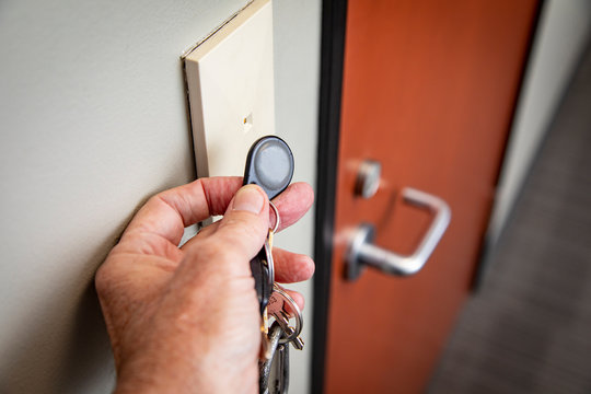 Close Up Of Hand Holding Key FOB To Gain Access To An Interior Office Door