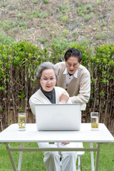 Using a laptop to wear an Asian elderly couple