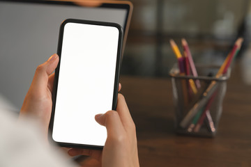 Closeup of young woman hand holding smartphone on the table and the screen is blank, social network concept.