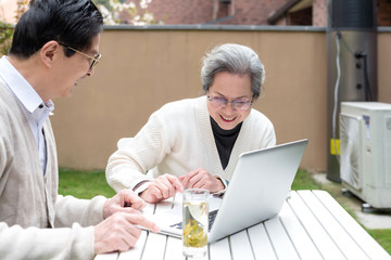 Using a laptop to wear an Asian elderly couple