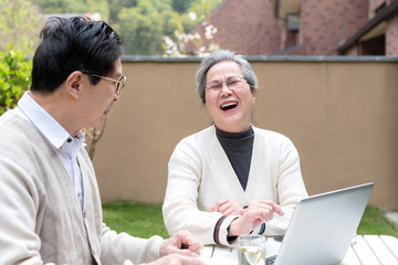 Using a laptop to wear an Asian elderly couple