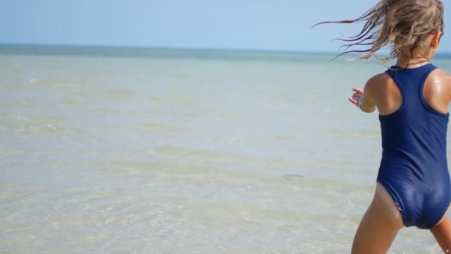 6 year old girl dancing in the sea in shallow water