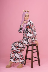 Portraiture of beautiful young Muslim girl wearing batik design dress known as Baju Kurung with hijab. Fashion for dinner, event and Eidul fitri feast. Studio shot with pink background.