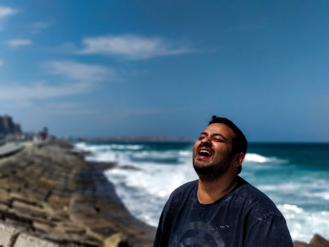 Man Laughing While Standing Against Sea And Sky
