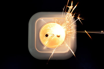 Concept electrical power safety. Sparks from a short circuit in chain in the electrical outlet on black background