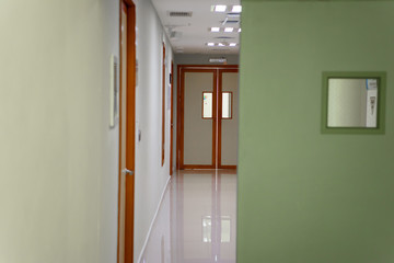 A huge brown door in a white corridor in a hospital.