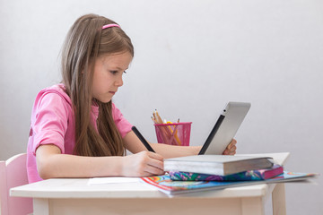 School girl studying at home with tablet and doing homework. Distance learning online education. Social distance during quarantine, self-isolation, online education concept, home schooler.copy space