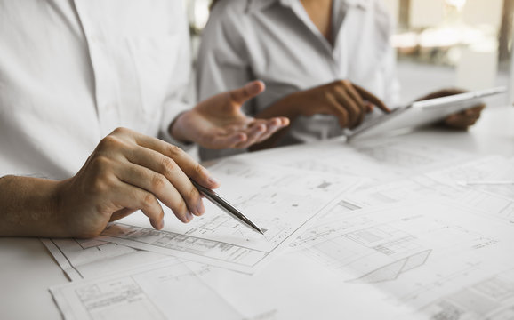 Architects engineer working with blueprints on table and discussing project together at the meeting in the office.