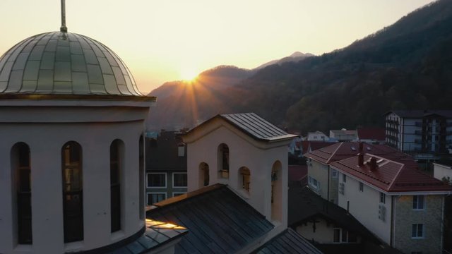 Aerial flight close to church dome at sunset in mountains in the Krasnaya Polyana of the city of Sochi