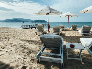 White soft sun loungers on the shore of a sandy sea beach. Tropical resort