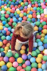 Fototapeta na wymiar Niña jugando en piscina de pelotas de colores.