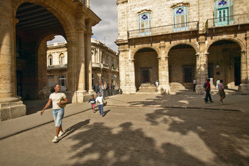A Cuban woman and child walking through an old Plaza in Old Havana, Cuba with archways