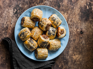 Homemade  sausage rolls. Minced puff pastry rolls - delicious snacks, tapas on brown background,...
