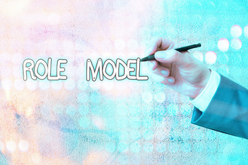 Conceptual hand writing showing Role Model. Concept meaning a demonstrating looked to by others as...