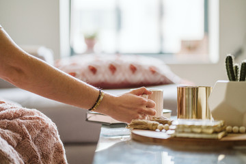 Women's Hand Picking Up Coffee From Modern Coffee Table