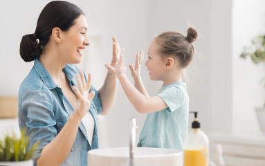 girl and her mother are washing hands