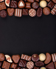 mix chocolate candy and other sweetness on blackboard background, sweet food frame