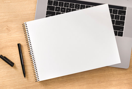 Online education concept Blank notebook with laptop and pen on wooden table top view