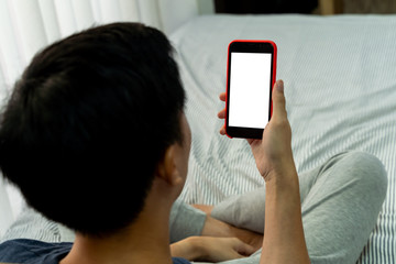 Unrecongnizable man hands holding smart phone on his hands with blank copy space on screen for any copy text message. Sitting comfortably on bed in bedroom - with mock-up copyspace