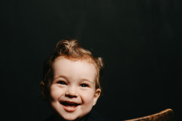 face of a happy smiling Caucasian child boy on a dark background