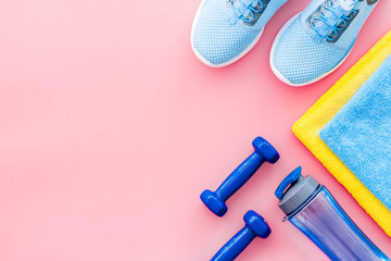 Athletics background with dumbbells, towel, sneakers on pink background top view copy space