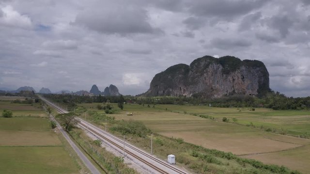 4K Aerial Scenic View fly over train track with of karst limestone formation hill in background. Bukit Keteri, Perlis. Push In Establish Shot