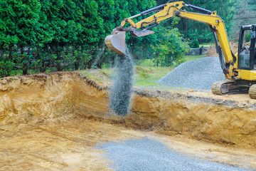 Working on a construction excavator moving gravel stones for foundation building © ungvar
