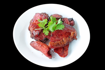 Scorched fried salted meat topping with coriander on white plate.