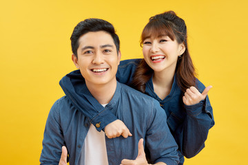 Portrait of smiling couple man and woman showing thumb up together while doing piggyback ride...