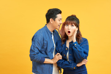 Image of handsome man whispering secret or interesting gossip to woman in her ear isolated over...