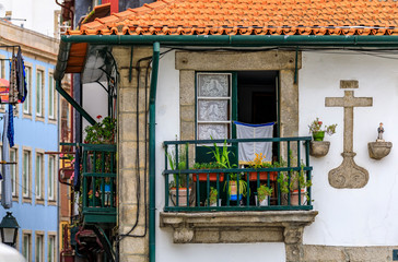 Fototapeta na wymiar Shabby facades and terracotta roofs of Portuguese houses with flower pots in the balconies of old town Porto, Portugal
